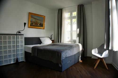 a bedroom with a bed and a window and a chair at Schillers Hotel & Café - GARNI - in Lüdenscheid