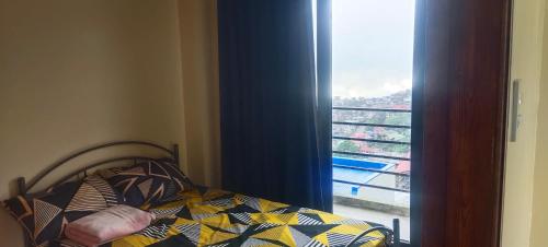 a bedroom with a bed and a window with a view at Hut on the Hill Baguio City in Baguio