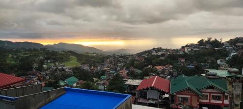 a view of a city with the sunset in the background at Hut on the Hill Baguio City in Baguio