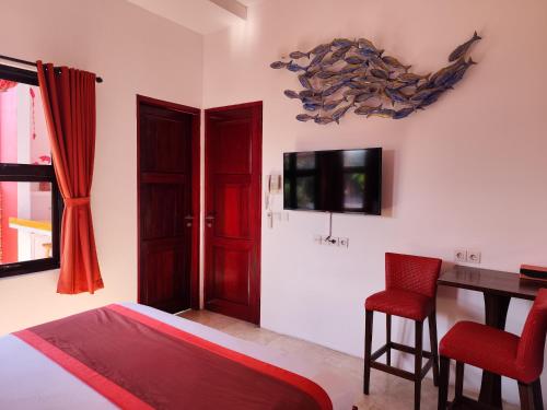a bedroom with a bed and a desk and a tv at Bali Ginger Suites & Villa in Seminyak