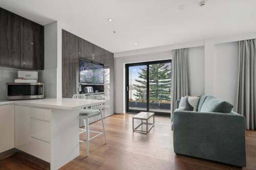 a kitchen and living room with a couch and a microwave at Bondi 38 Serviced Apartments in Sydney