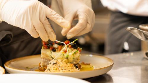 a person cutting a piece of food on a plate at Logis hôtel Restaurant Le Faisan Dore in Fontenai-sur-Orne