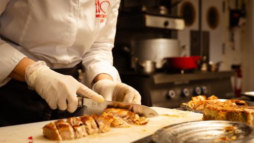 a person in a kitchen cutting food with a knife at Logis hôtel Restaurant Le Faisan Dore in Fontenai-sur-Orne
