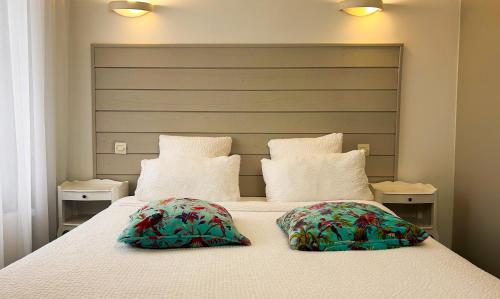 a bedroom with a large bed with two pillows at Logis hôtel Restaurant Le Faisan Dore in Fontenai-sur-Orne