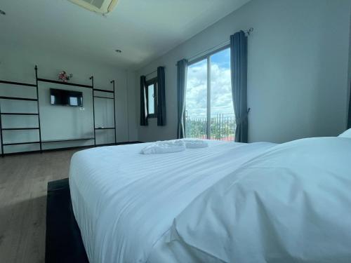 a white bed in a bedroom with a large window at Lamoon Trang in Ban Phlu Phli