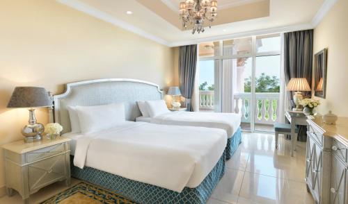 a bedroom with two beds and a chandelier at Kempinski Hotel & Residences Palm Jumeirah in Dubai