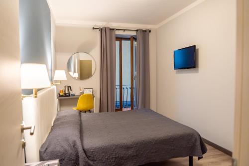 a bedroom with a bed and a yellow chair at Hotel Romagna in Baveno