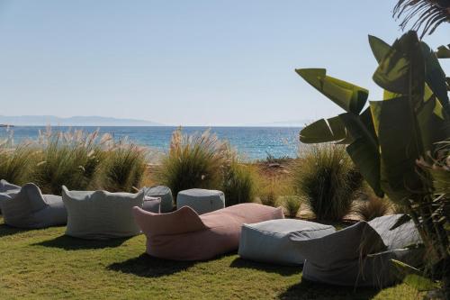 a row of pillows sitting on the grass near the ocean at Eden Beachfront Residences & Suites in Kastraki Naxou