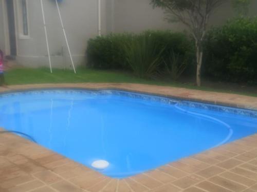 a large blue swimming pool in front of a house at Jo's Eden in Edenvale