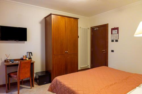 a bedroom with a bed and a desk and a cabinet at Hotel Romagna in Baveno