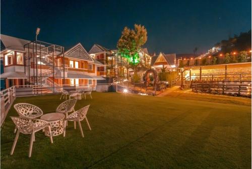 a group of tables and chairs on a lawn at night at Kanavu Valley View in Ooty