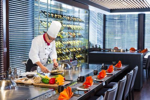 a chef preparing food in a restaurant kitchen at Queena Plaza Hotel in Yongkang