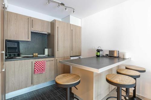 une cuisine avec des armoires en bois et un comptoir avec des tabourets dans l'établissement Magnificent apartment with parking - AC-balcony, à Cannes