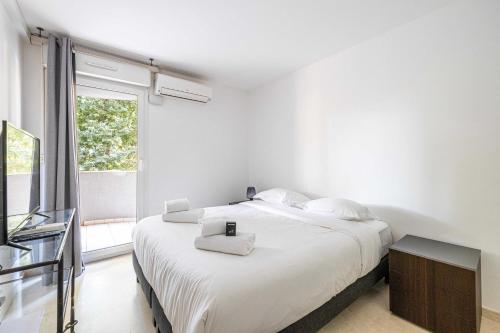une chambre blanche avec un grand lit et une fenêtre dans l'établissement Magnificent apartment with parking - AC-balcony, à Cannes