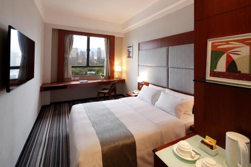 a hotel room with a bed and a desk and a window at B P International in Hong Kong