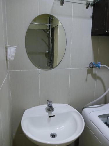 un bagno con un lavandino bianco e uno specchio di Breeze Residences a Manila