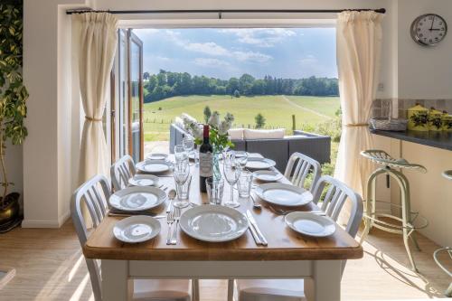 a table with plates and glasses on it in a room with a window at Holly Cottage in Cranleigh