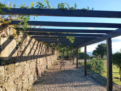 a stone wall with a wooden pergola at Vinte-Quinta da Boavista in Ponte de Lima