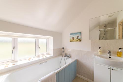 a white bathroom with a sink and a window at Holly Cottage in Cranleigh
