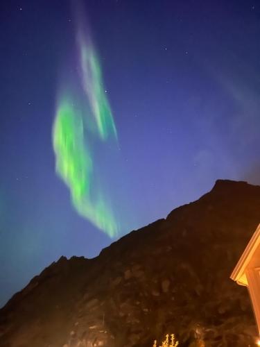 an aurora sign in the sky over a mountain at Lofoten Sea Lodge in Sennesvik