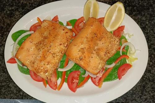 two pieces of fish on a plate with vegetables at Pecan Farm Guesthouse in Louis Trichardt