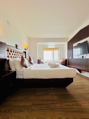 a large bedroom with a large bed and a television at Kanavu Valley View in Ooty