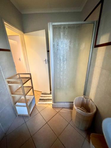 a bathroom with a sliding glass door with a basket at Centurion La Creme Apartments in Centurion