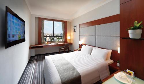 a hotel room with a bed and a desk and a television at B P International in Hong Kong