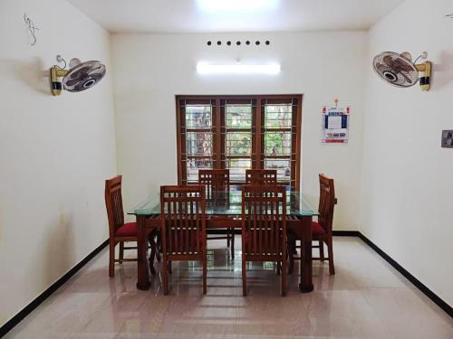 ein Esszimmer mit Glastisch und Stühlen in der Unterkunft Krishnasila Homestay in Varkala