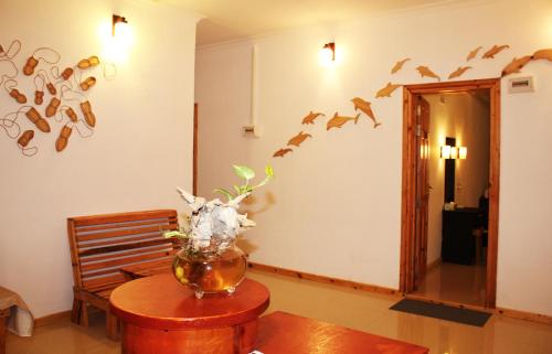 a room with a vase on a table with birds on the wall at Kaafu Inn Guraidhoo in Guraidhoo