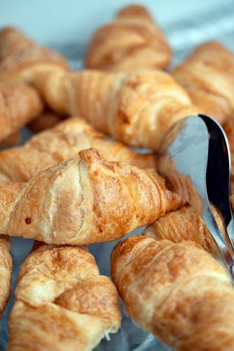 a pile of croissants with a spatula on a table at Hotel Amadeos - Matosinhos - Porto in Matosinhos