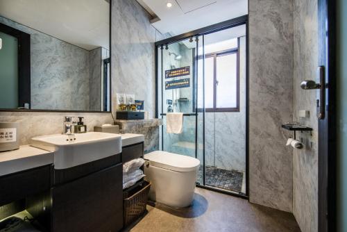 a bathroom with a toilet and a sink and a shower at Fenghuang Jiang'an Xinghe Hotel in Fenghuang