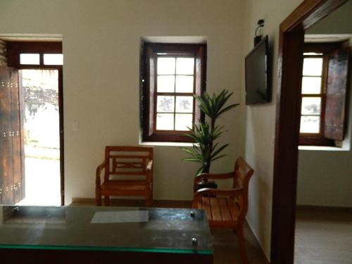 a room with a table and chairs and windows at Pousada Portal da Lua in São Thomé das Letras
