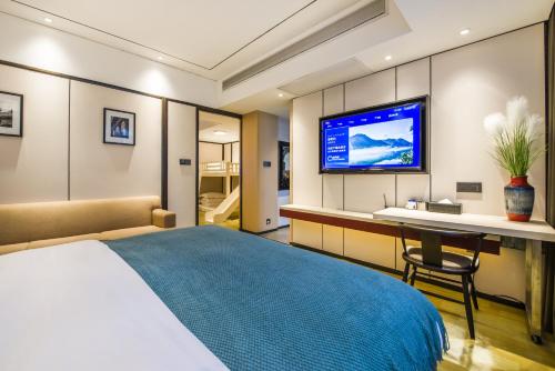 a bedroom with a bed and a desk and a tv at Fenghuang Jiang'an Xinghe Hotel in Fenghuang