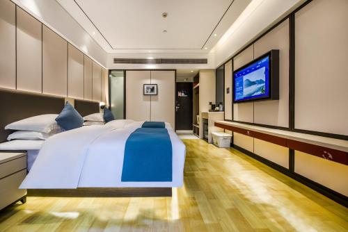 a bedroom with a large bed and a flat screen tv at Fenghuang Jiang'an Xinghe Hotel in Fenghuang