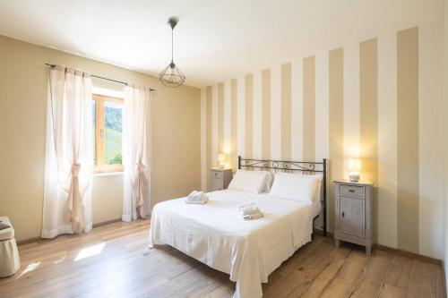 a bedroom with a white bed and a window at Le Casaline by VacaVilla in Tepolini