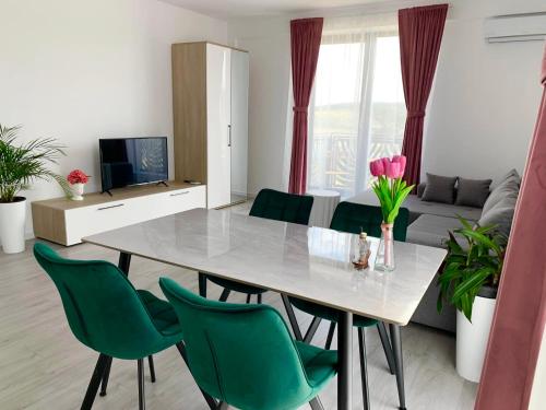 - un salon avec une table et des chaises vertes dans l'établissement Apartament Denisa Baile Felix, à Cordău