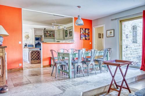 une salle à manger aux murs orange avec une table et des chaises dans l'établissement La Rocherie - Charmante maison avec piscine privée, à Carnac