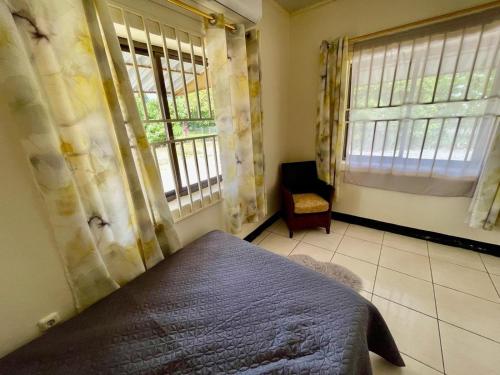 a bedroom with a bed and two windows and a chair at 3 Bed House - Sleeps 6 - Garden - Parking - Wifi in Paramaribo