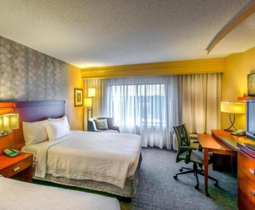 a hotel room with a bed and a desk at Courtyard Greensboro Airport in Greensboro
