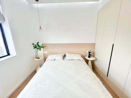 a small white bedroom with a bed and two tables at Eastern Hub - Three Bedroom Apt in Xintiandi, 50m from Metro, Many Shops and Malls Surrounded in Shanghai