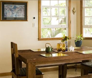 een houten tafel in een kamer met 2 ramen bij Ka'awa Loa Plantation in Captain Cook