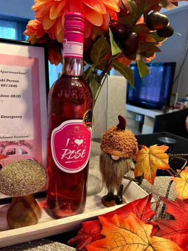 a bottle of wine sitting next to a vase with flowers at Cseppecske Apartman in Pécs