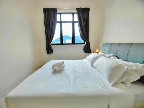 a stuffed animal sitting on top of a white bed at The Sun Residence Bayan Lepas in Bayan Lepas