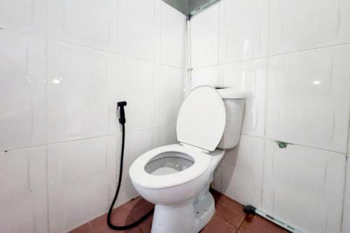 a bathroom with a white toilet with a hose at RedDoorz at Marina City Waterfront in Pembunuh