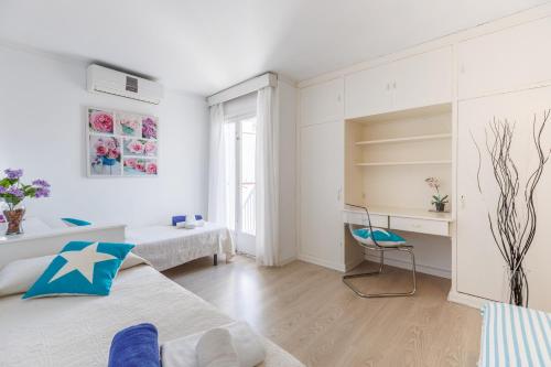 a white room with two beds and a chair at Marian Gola in Port de Pollensa