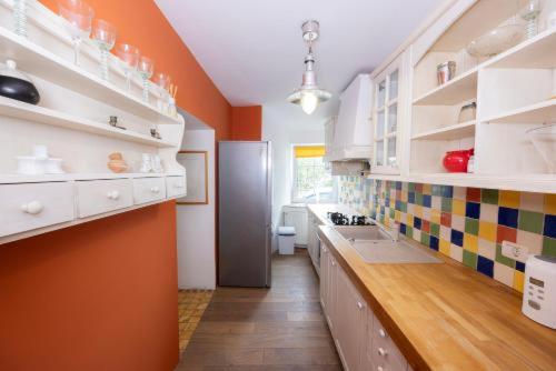 a large kitchen with orange walls and white cabinets at Hiša Linhart, Hotel & Restaurant in Radovljica