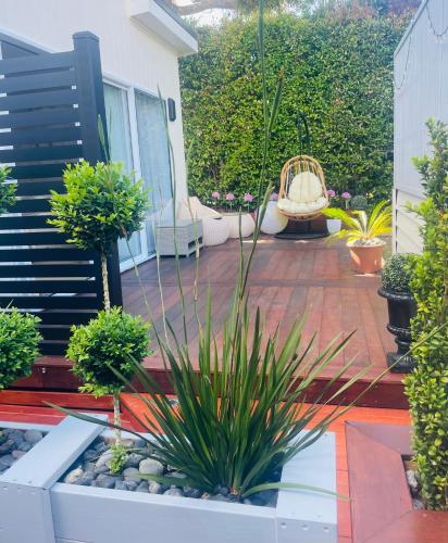 a garden with a patio with plants and a chair at Delightful little house & Chateau Charme Suite in Auckland
