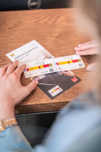 a person holding two credit cards on a table at Hotel Frangart an der Weinstraße in Appiano sulla Strada del Vino