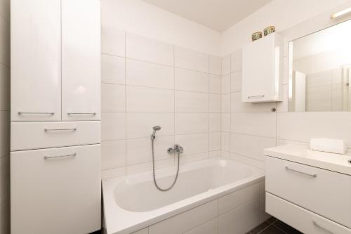 a white bathroom with a tub and a sink at Highland Moments Apartment - by myNests in Gröbming